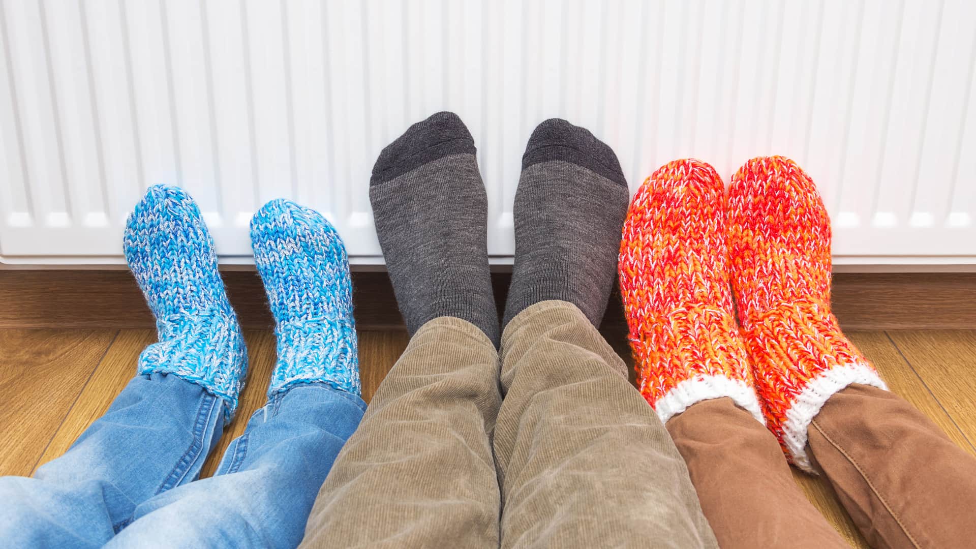 familia con calcetines calentando sus pies en un radiador porque pagan una de las tarifas tur de iberdrola