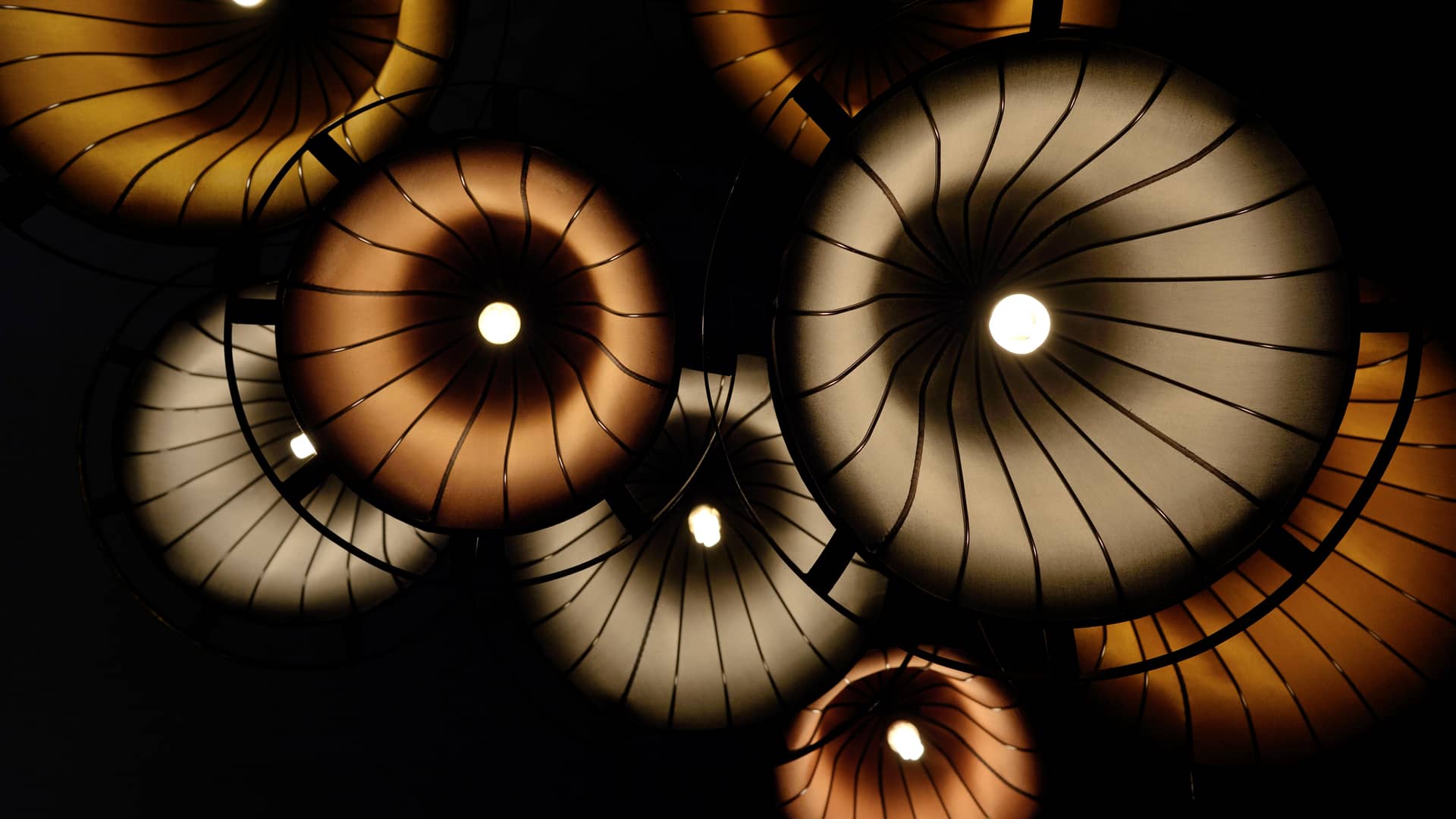 Vista inferior de un conjunto de lámparas con pantallas de colores cálidos, iluminadas gracias a una tarifa de luz de imagina energía