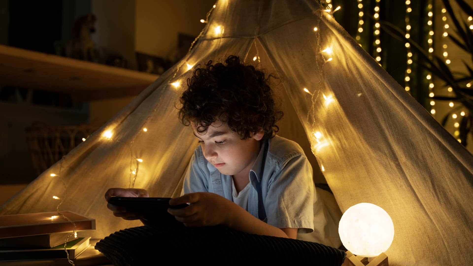 Niño jugando a videojuegos desde su tipi iluminado gracias a su tarifa de insignia energía
