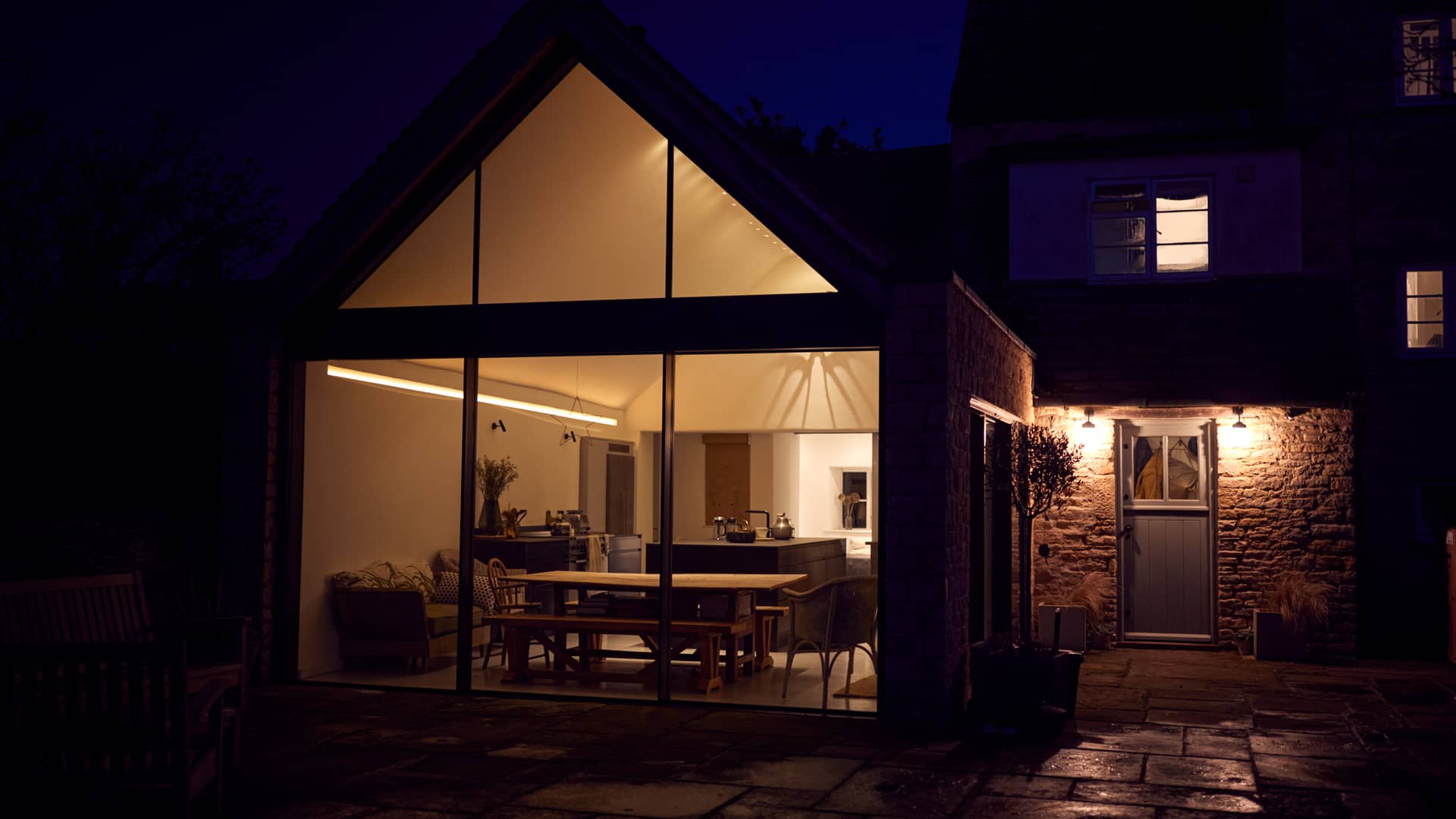 casa con paredes de cristal iluminada por la noche que representa las tarifas por uso de naturgy