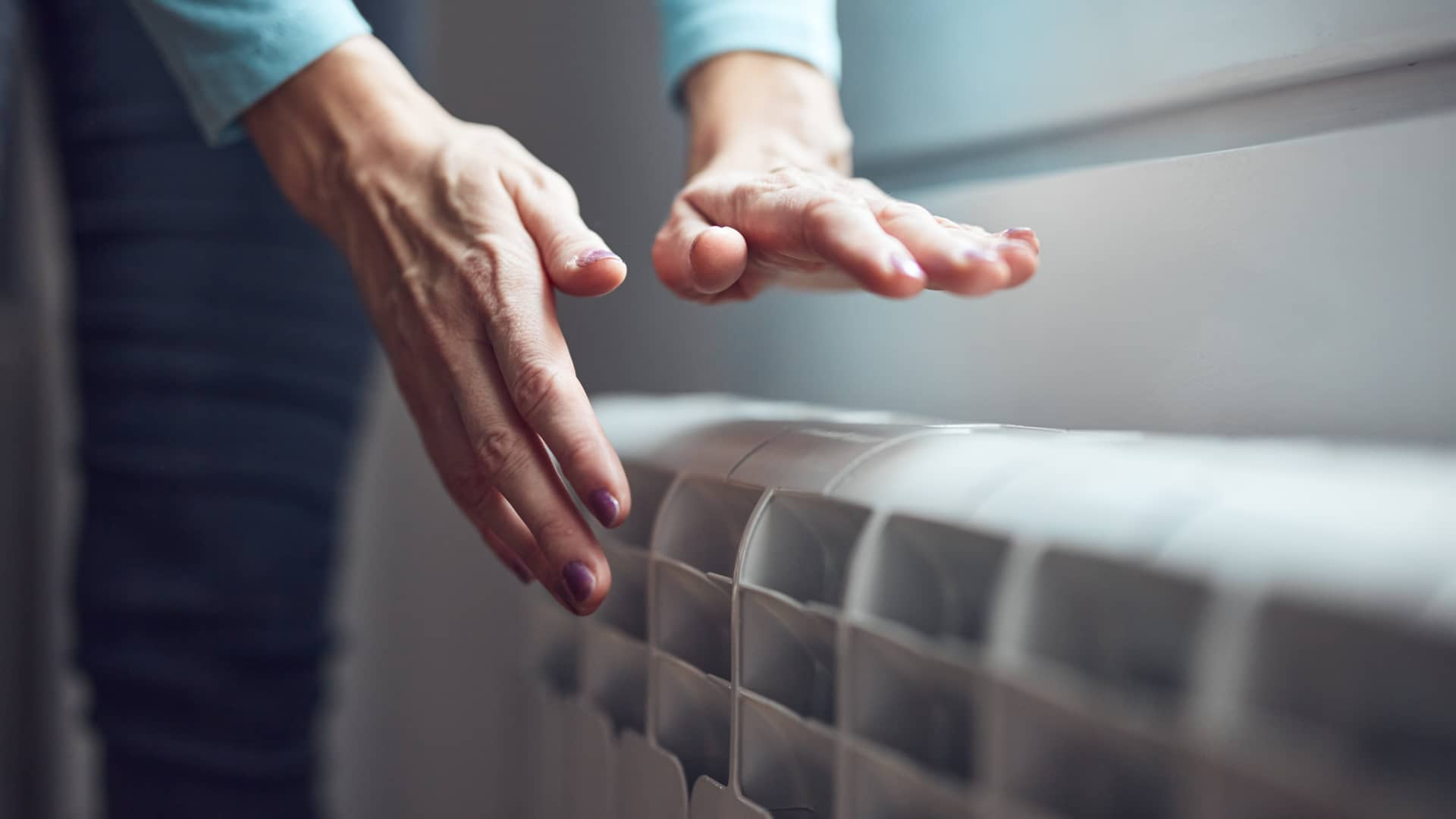 manos de una mujer calentandose en un radiador gracias a una de las tarifas tur de naturgy