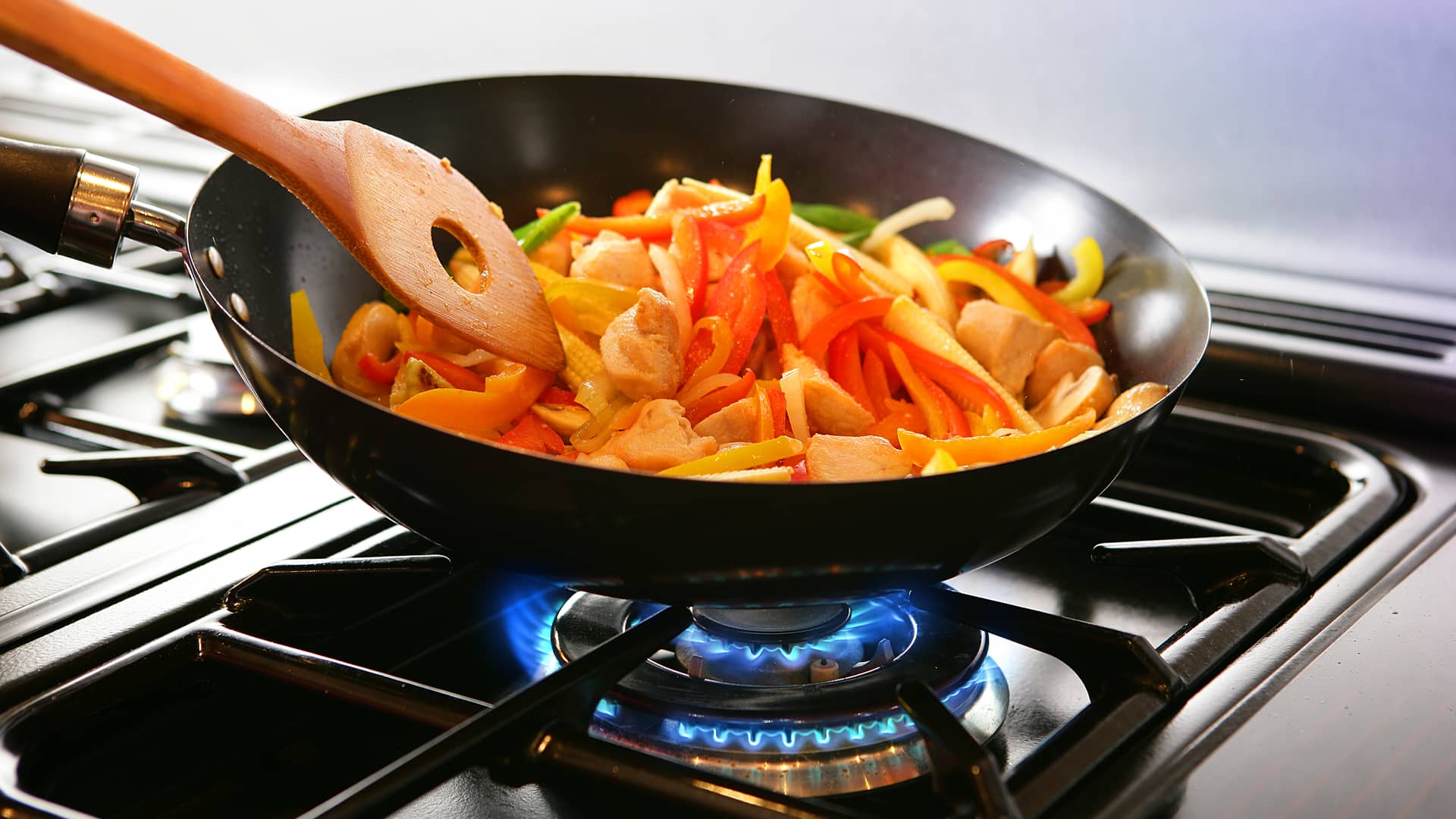 Persona haciendo un wok en su cocina de gas redexis