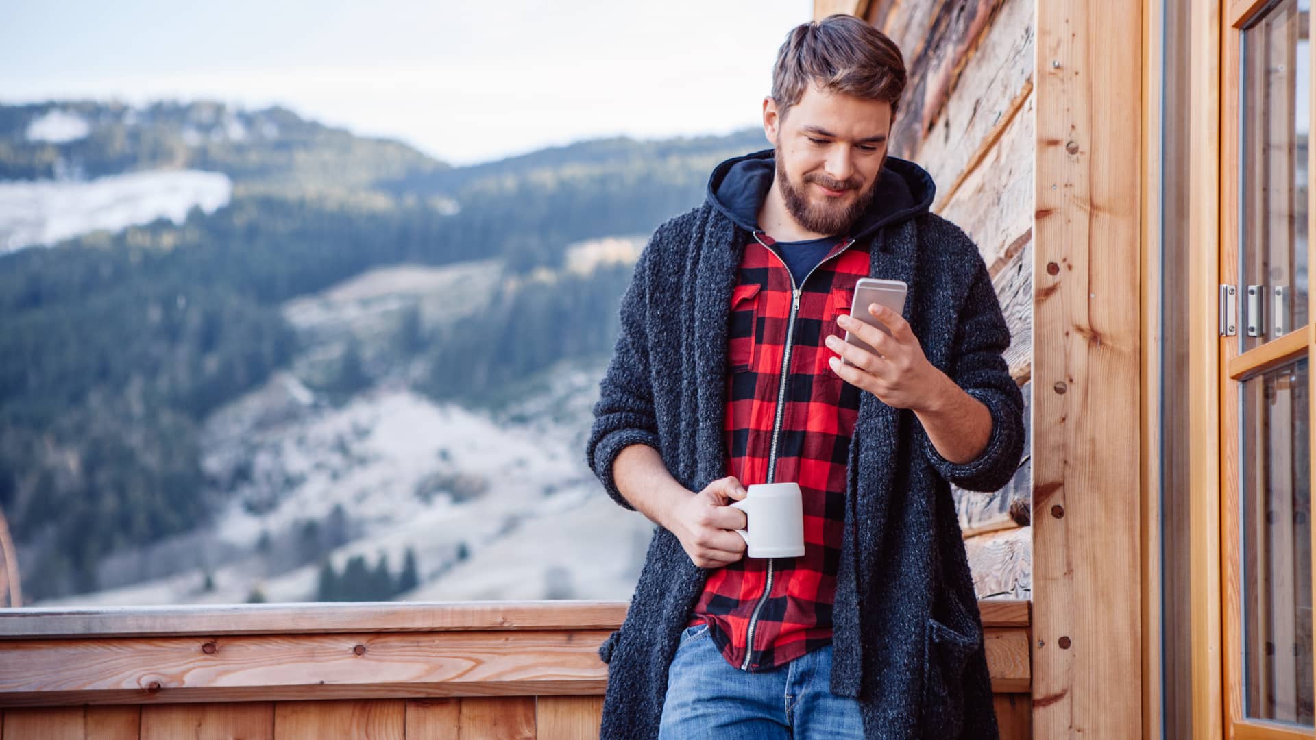 Hombre buscando en su smartphone el teléfono de unielectrica mientras toma un café