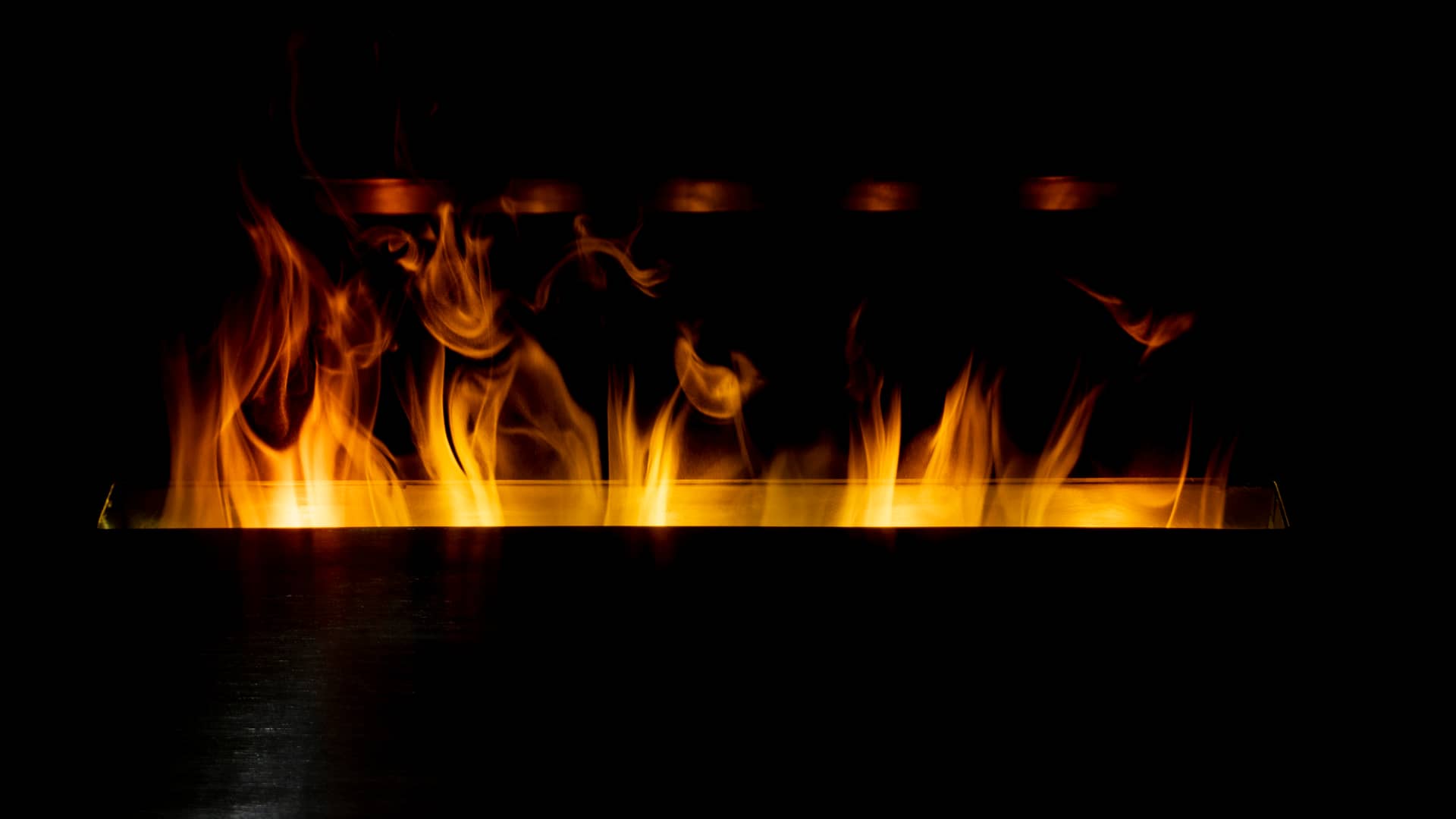 Llamas saliendo de una estufa rectángular de bioetanol gracias al quemador de la misma