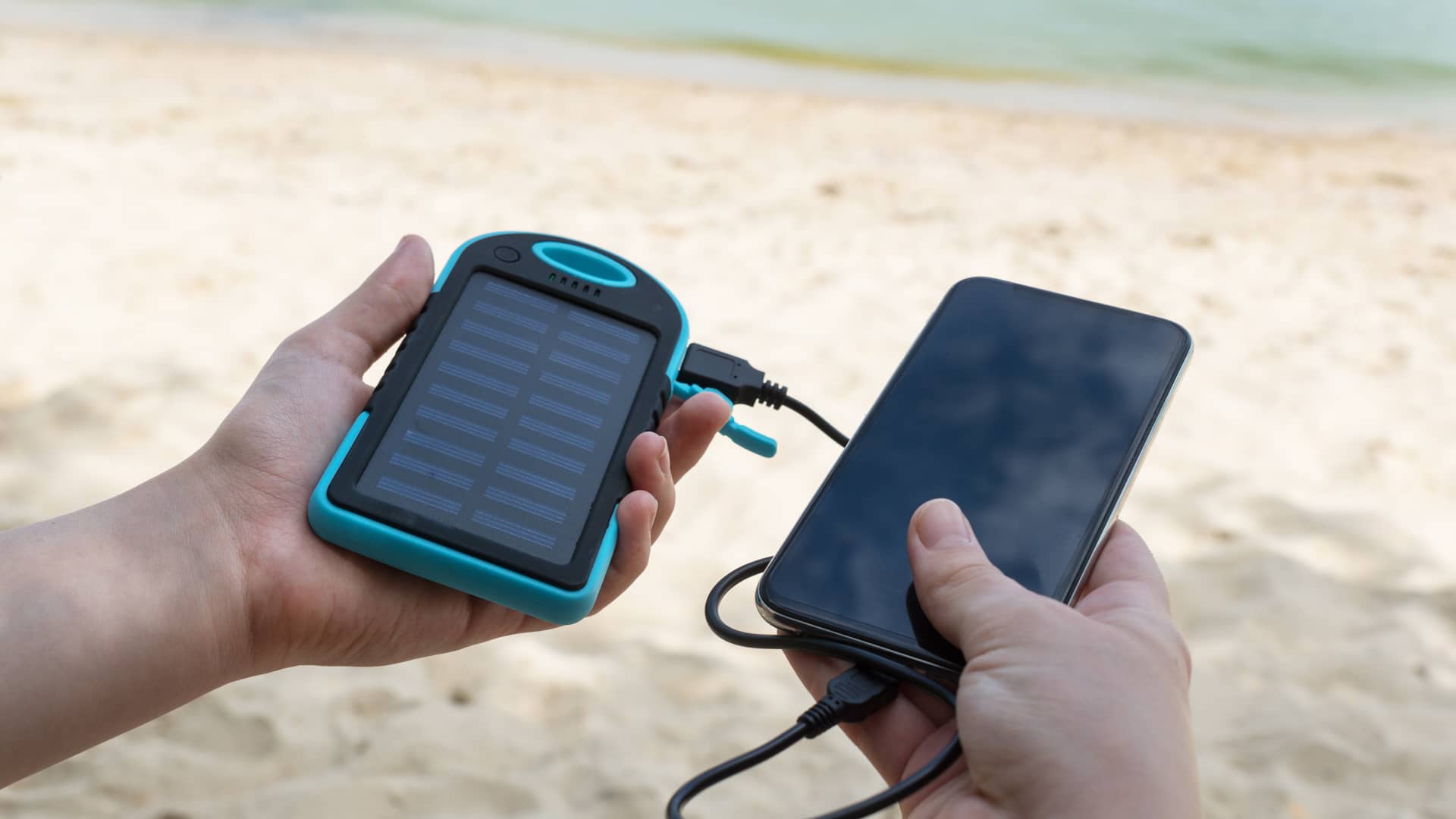 Persona espera mientras su móvil comienza a cargarse gracias a un cargador solar de USB, similar a los que se pueden hacer de forma casera