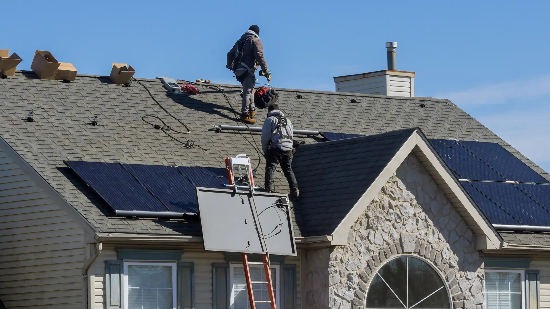 Tencios instalando placas solares en el techo de una casa como esquema de instalacion de elementos de auconsumo de energia solar