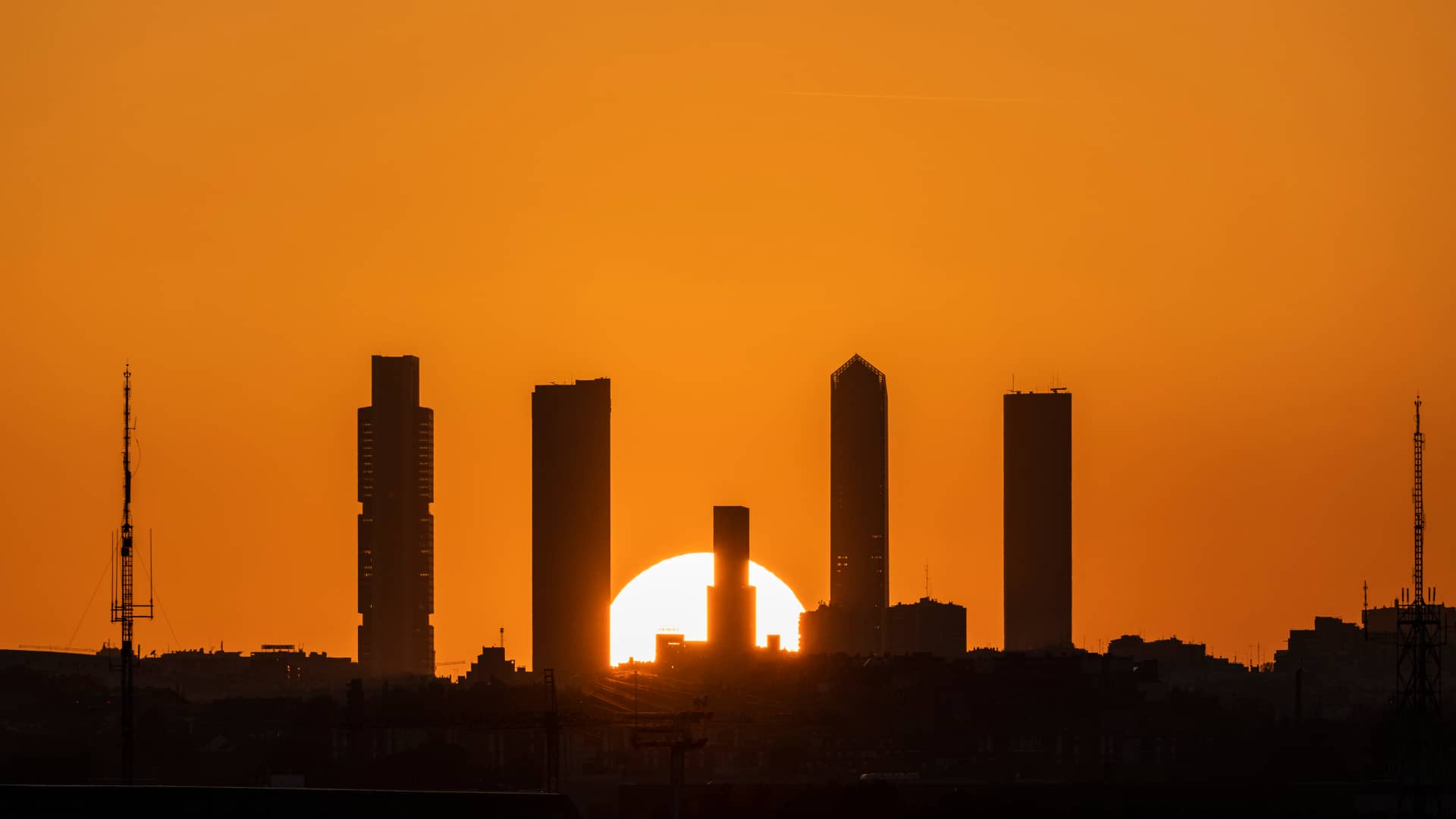 Puesta de sol con un cielo anaranjado por la calima, se aprecia el skyline de Madrid, en nuestro mapa podrás ver el índice solar de radiación de España para una instalación de energía solar más eficiente 