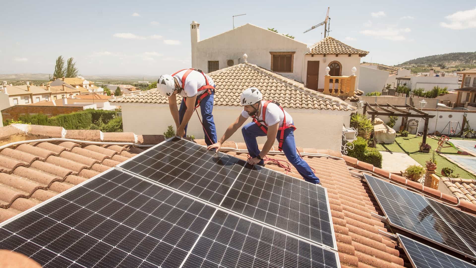 Técnicos instalando paneles solares en el tejado de una casa tras escoger los soportes idóneos para ese tejado