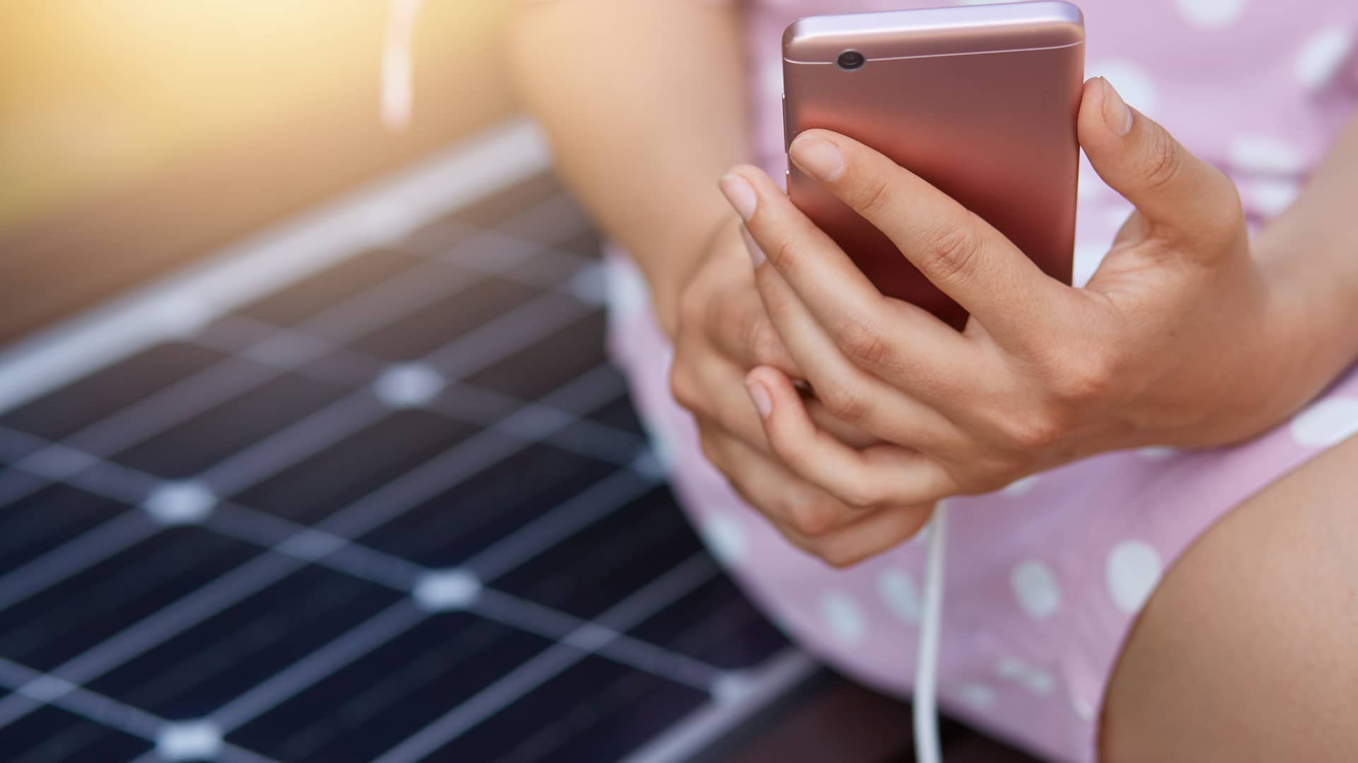Mujer cargando su smartphone gracias a una placa solar, a continuación detallaremos otros usos de la energía solar renovable