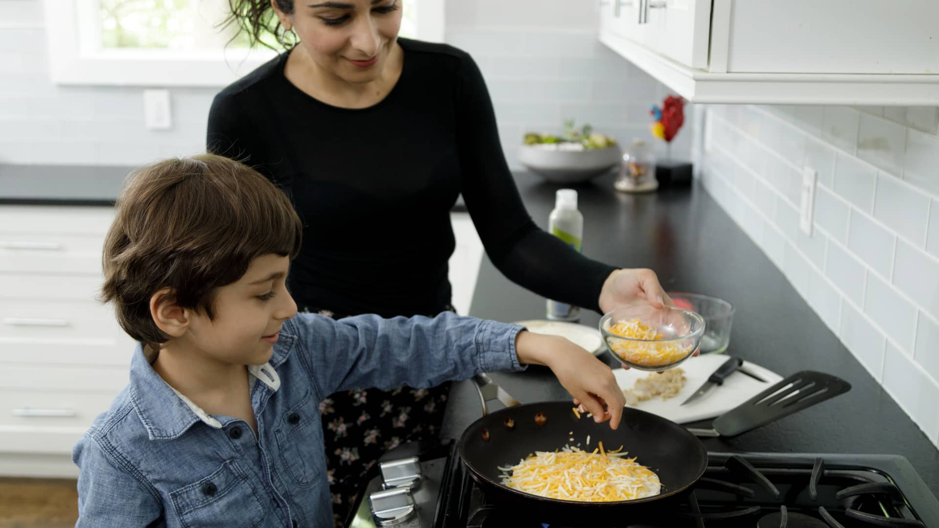 Madre que recibe el bono social en luz cocinando con su hijo