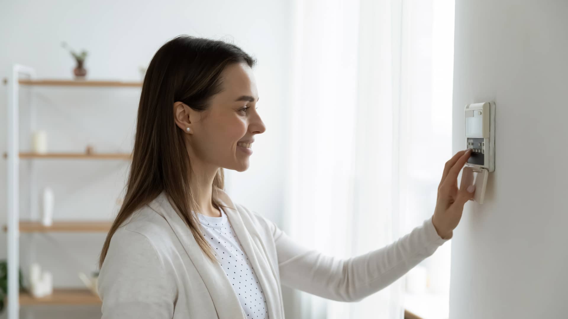 Mujer regulando termostato de su hogar con certificado energético