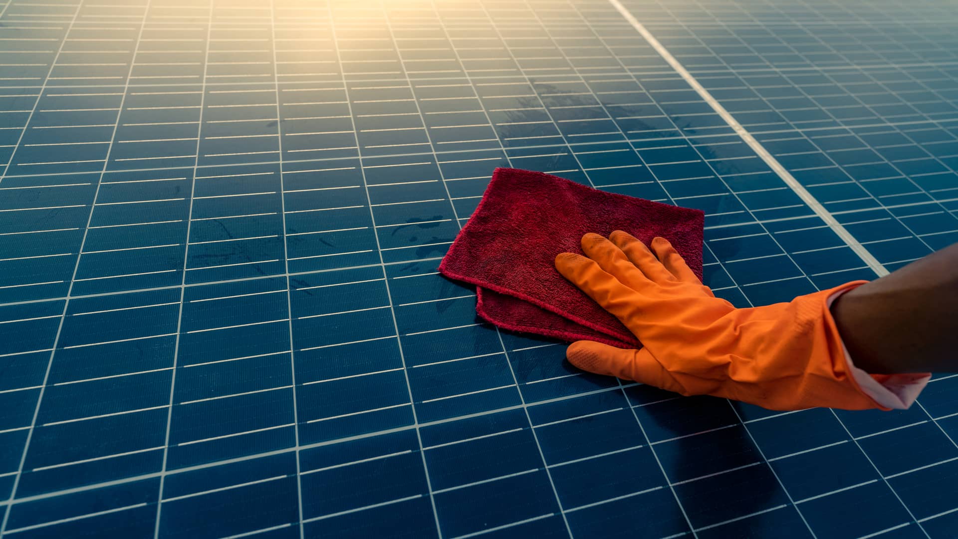 Una persona realiza el mantenimiento de sus placas solares, limpiandolas con una gamuza suave