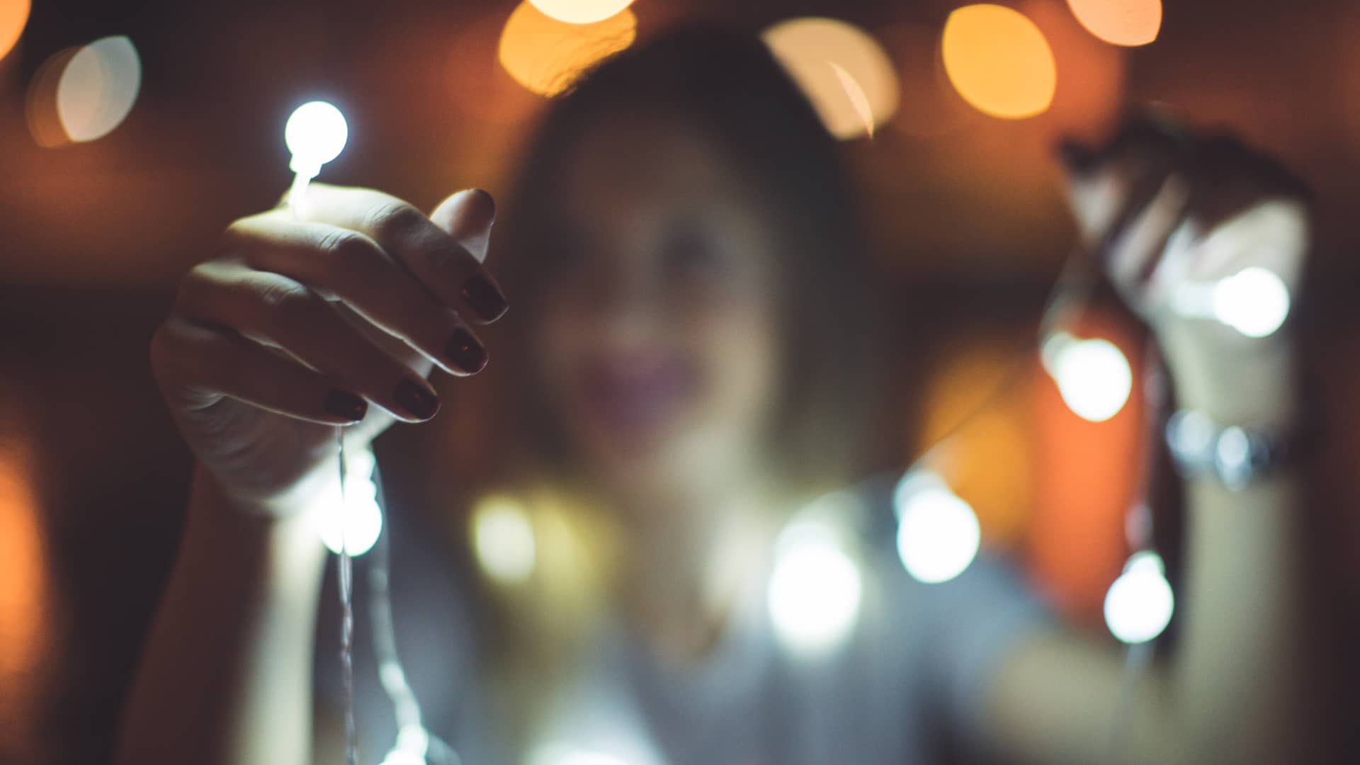 Mujer, que disfruta de una tarifa de luz con precio indexado, coloca una guirnalda de luces de navidad